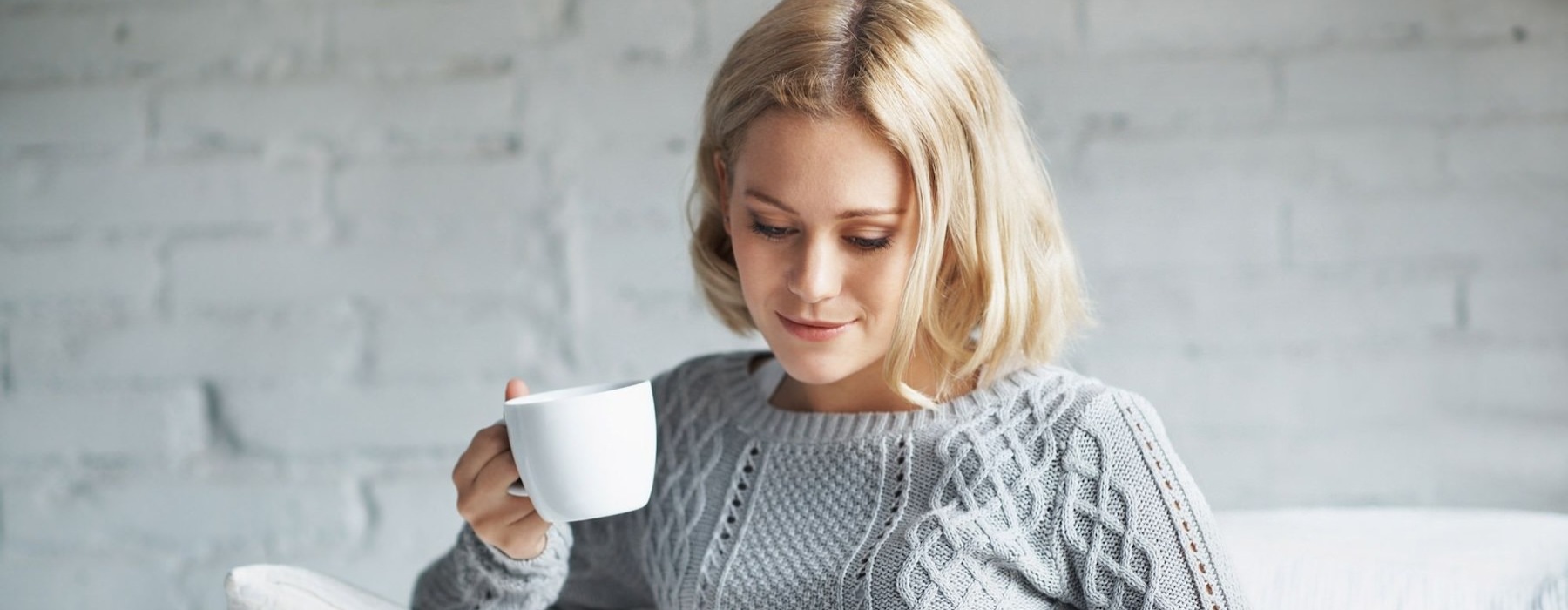 a person sitting down holding a cup looking at a tablet