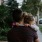 tired little girl rests her head on her father's shoulder as he carries her down the city sidewalk
