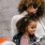 mother and daughter stick their tongues out while looking at themselves in a motorcycle mirror parked in front of a building