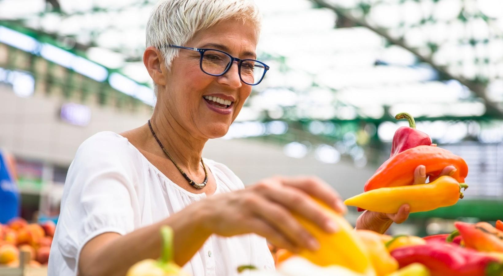 Vibrant community life with a variety of dining options a woman smiling and holding a bunch of vegetables